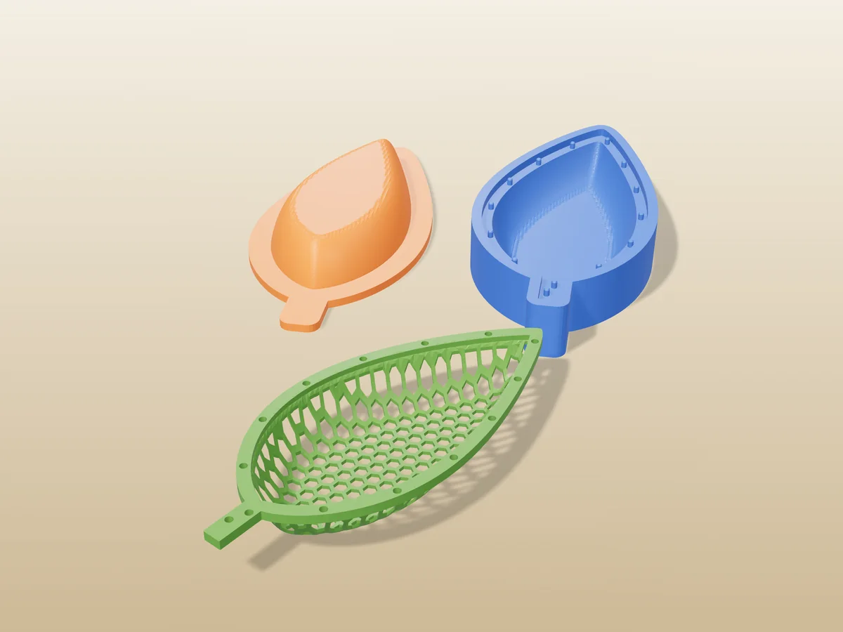 3D render of a green leaf shaped honeycomb mesh dish with a stem, in front of the orange and blue press halves that form it
