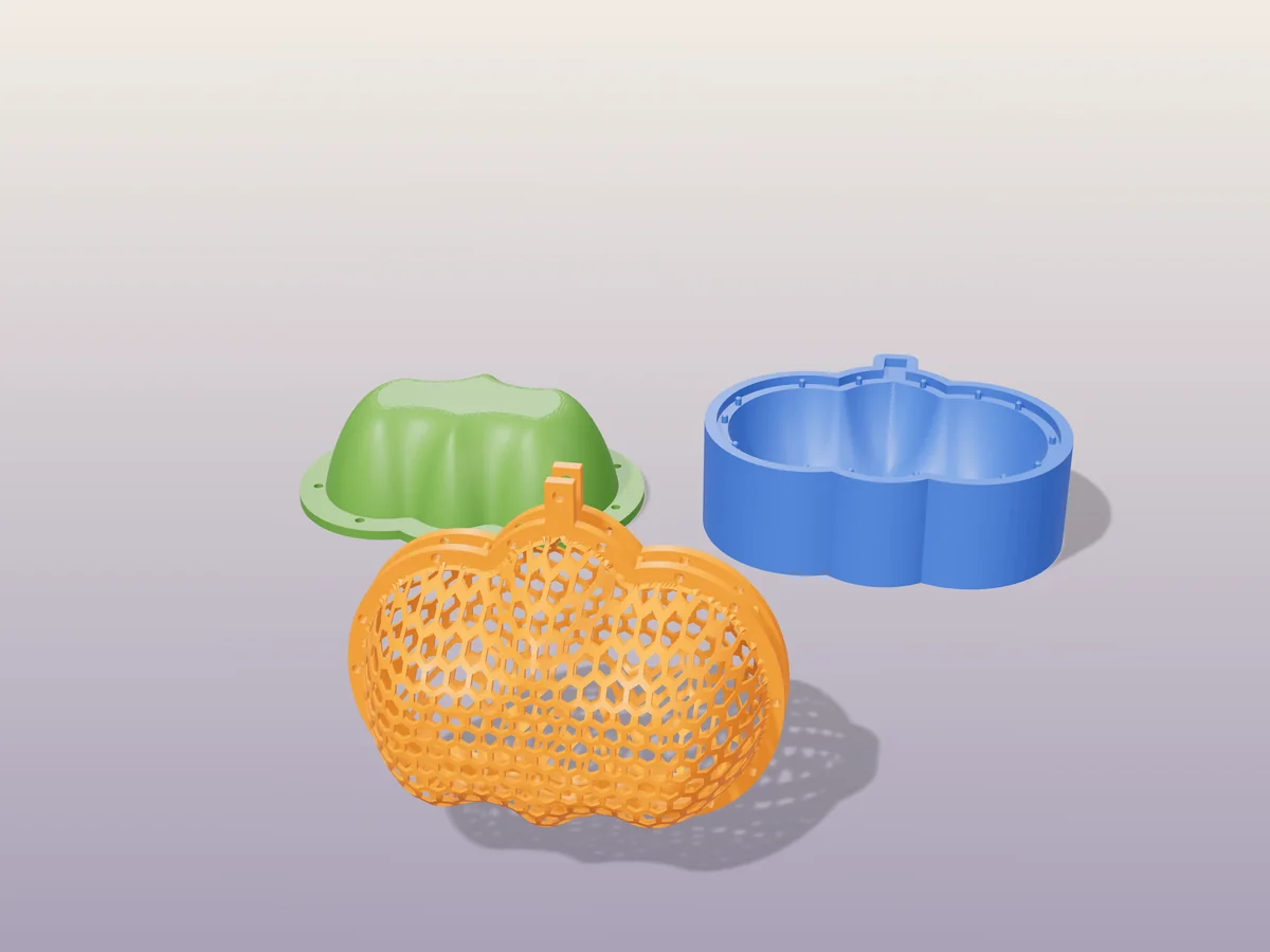 3D render of an orange honeycomb mesh pumpkin with a stem and hanging hole, in front of the green plug and blue cavity that press it into shape