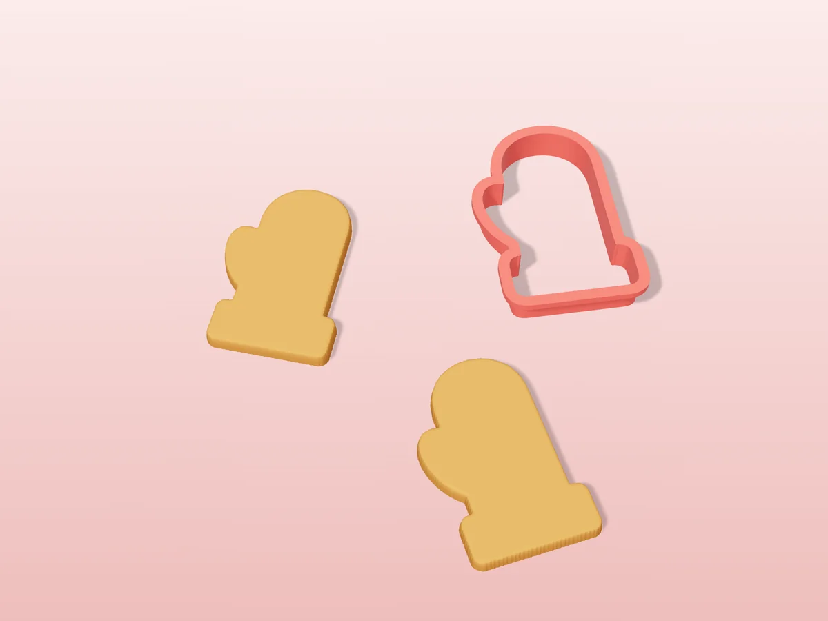 3D render of a coral red 3D-printed mitten cookie cutter next to two golden baked cookies in the same shape