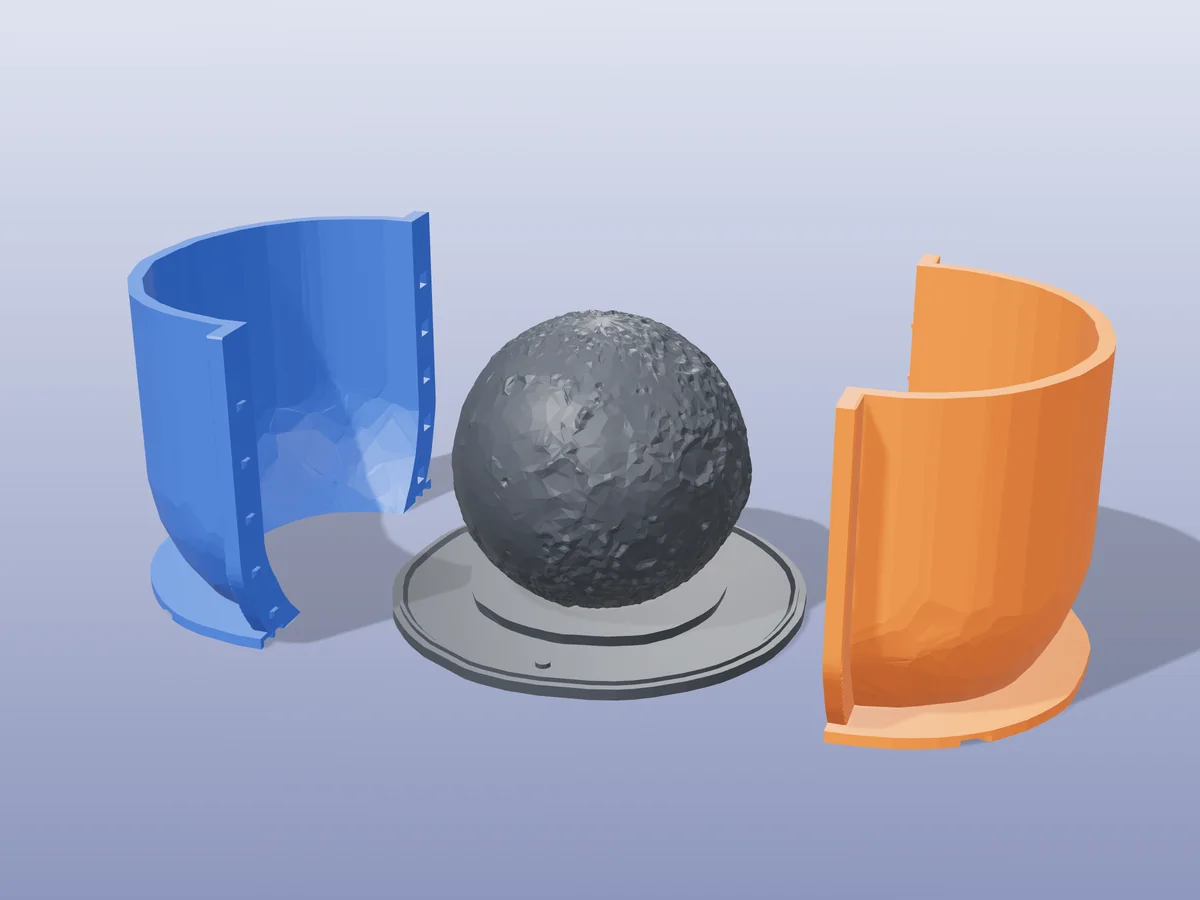3D render of the cratered Moon master fused on its printed charcoal base, between the orange and blue hugging shell halves