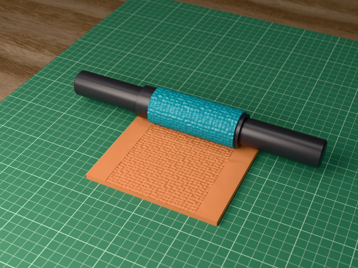 3D render of the printed mosaic tile textured rolling pin, its patterned sleeve between two dark handles, resting on a slab of clay it has pressed with mosaic tesserae