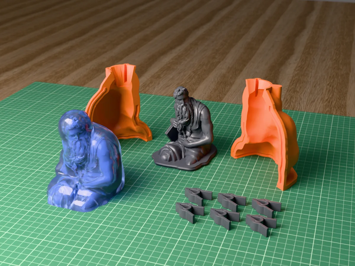 3D render of the Moses master on its printed charcoal base between the two orange hugging-shell halves, with the six printed clamps and the cured translucent blue silicone mold in front