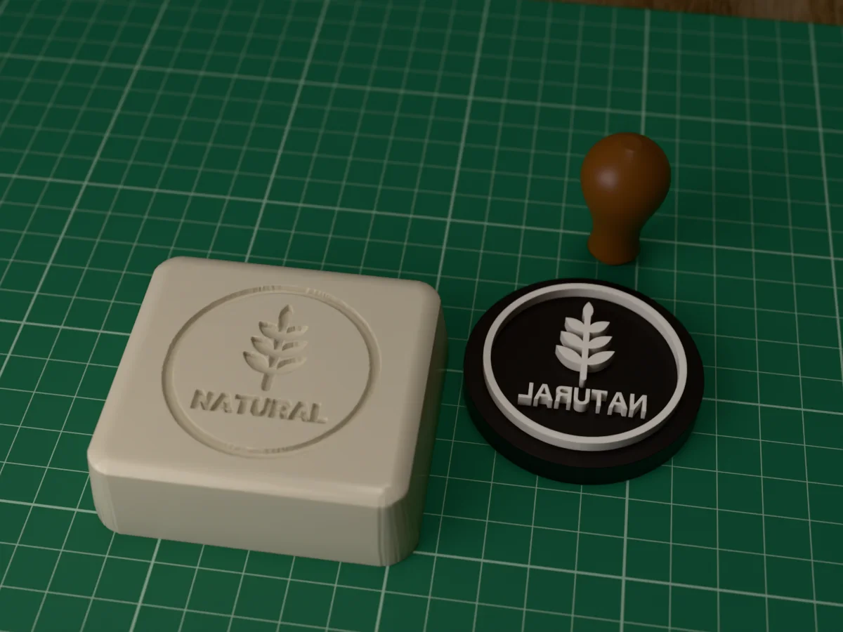 3D render of the printed natural soap stamp, face up next to its brown handle, and a bar of soap with the stamp pressed into it