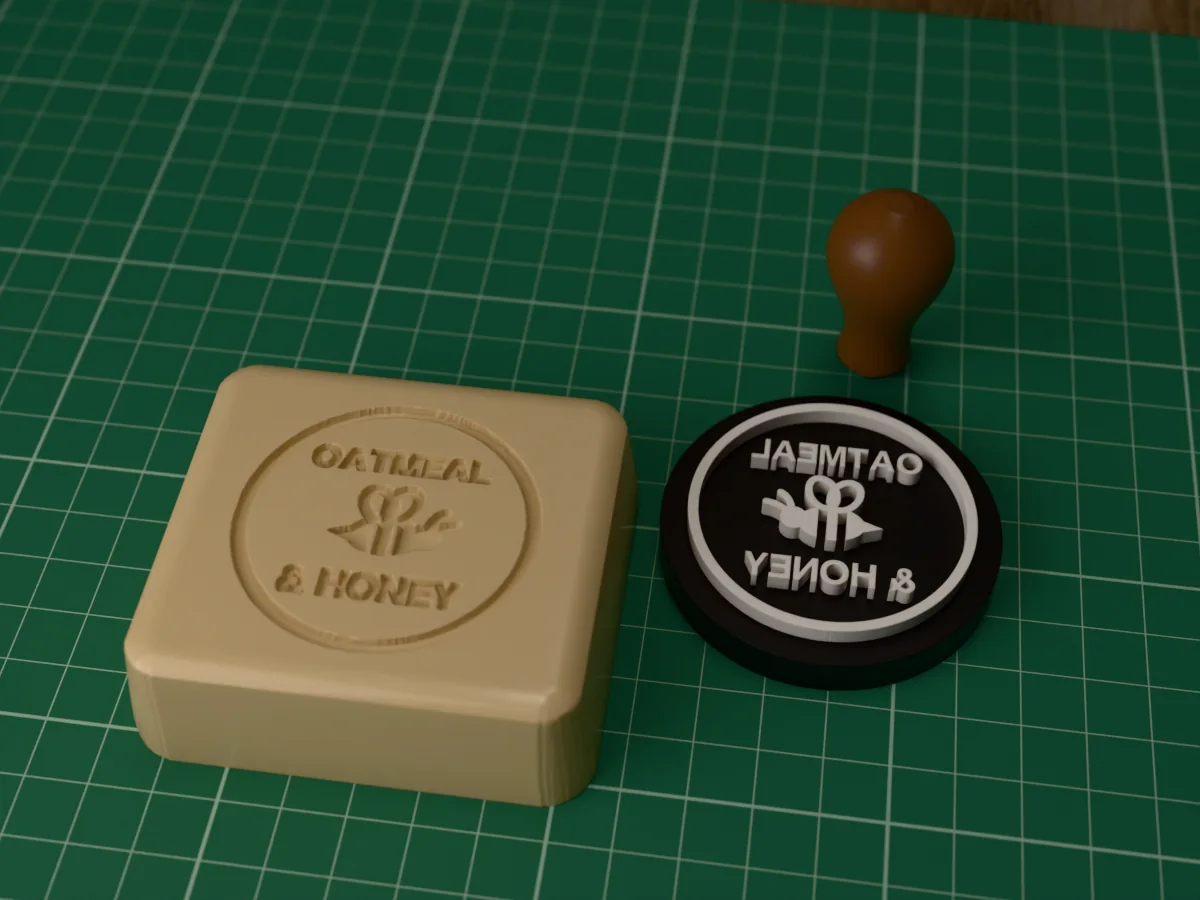 3D render of the printed oatmeal and honey soap stamp, face up next to its brown handle, and a bar of soap with the stamp pressed into it