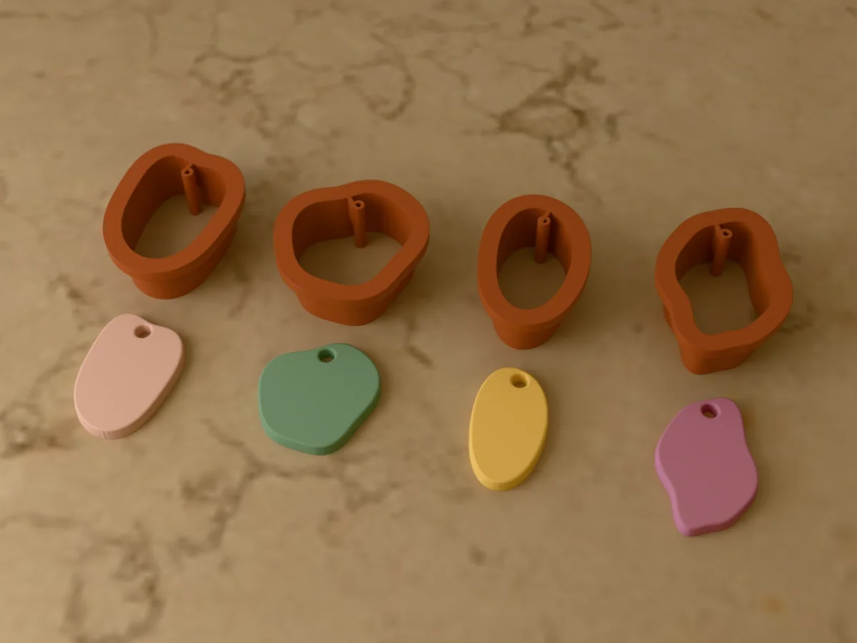 3D render of four 3D-printed rust brown polymer clay earring cutters (organic drop 34 mm, pebble 30 mm, bean 32 mm and wavy drop 36 mm) with the clay earring pieces they cut in front