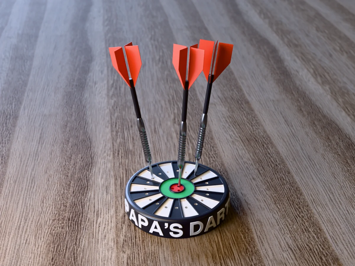 3D render of the printed personalized dart holder: a round black case with PAPA'S DARTS raised in white round its side, a black and white dartboard face with a green ring and red bullseye, and three darts standing in it