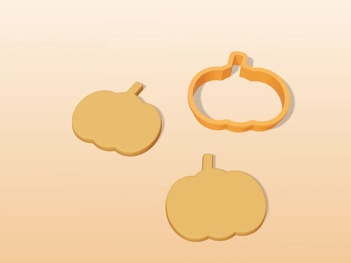 3D render of a orange 3D-printed pumpkin cookie cutter next to two golden baked cookies in the same shape