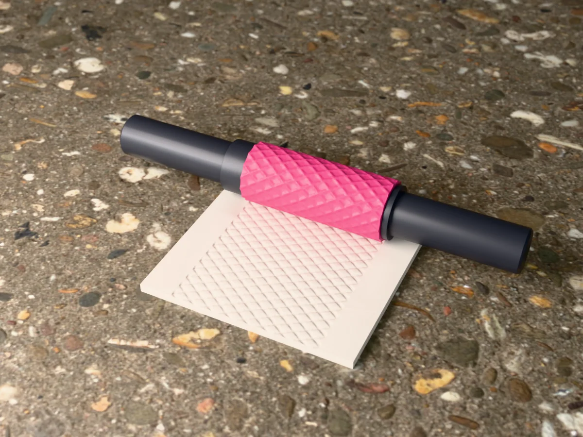 3D render of the printed quilted diamond textured rolling pin, its patterned sleeve between two dark handles, resting on a slab of clay it has pressed with quilted diamonds