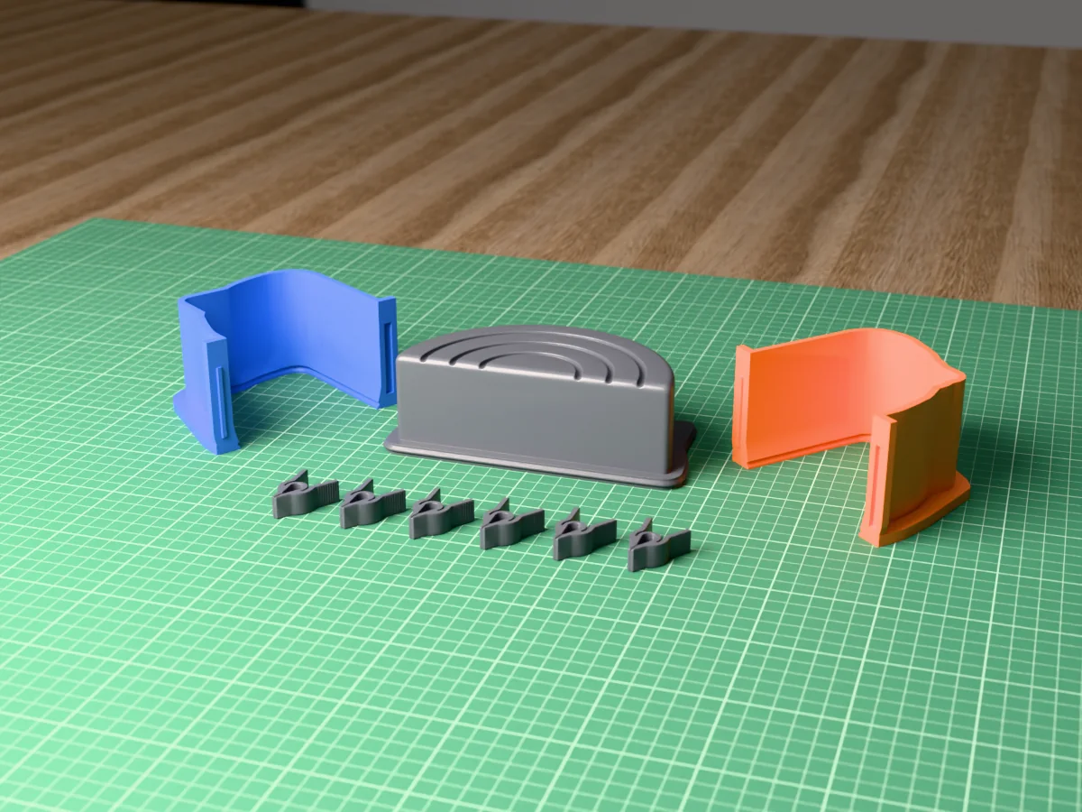 3D render of the rainbow arch bookend master lying on its back, fused on its printed charcoal base between the orange and blue shell halves, with the charcoal clamps in front