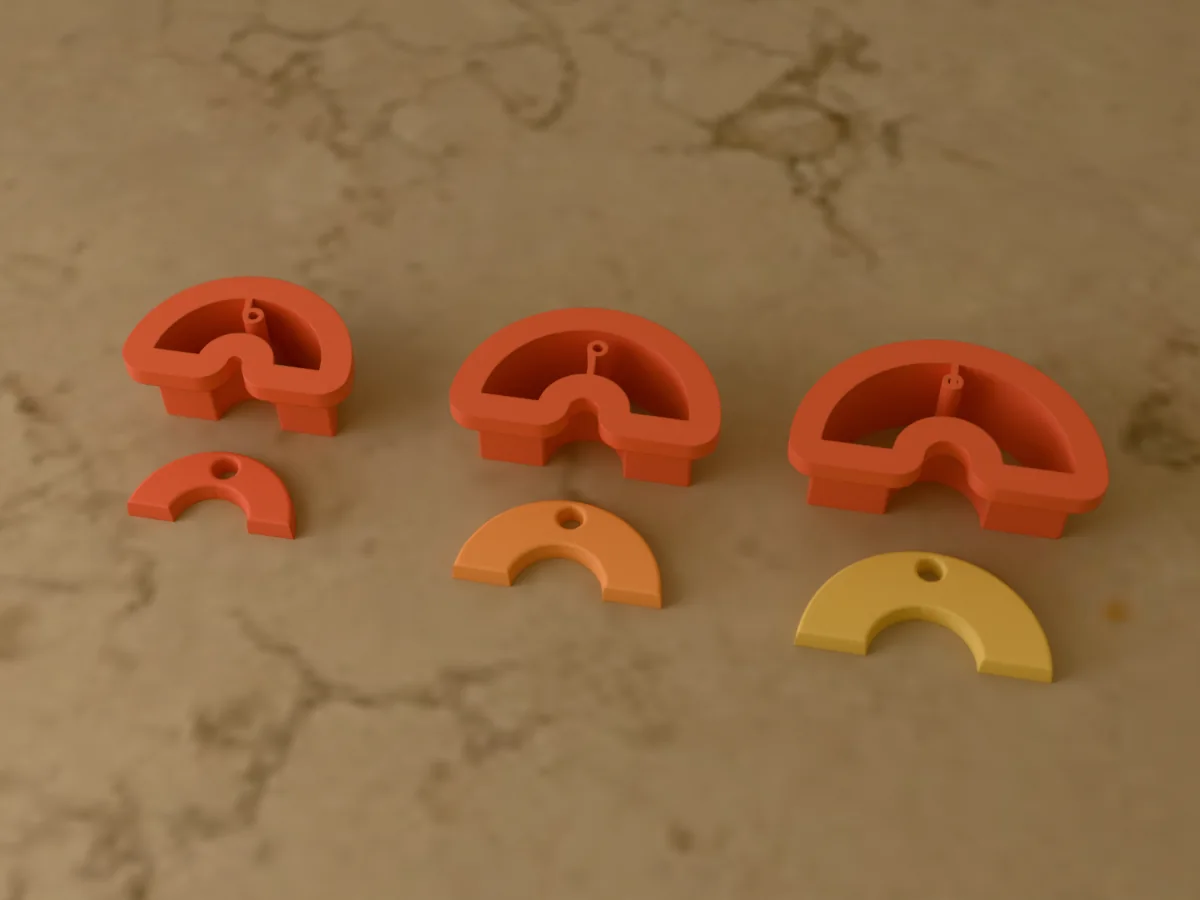 3D render of three 3D-printed coral polymer clay earring cutters (rainbow 25 mm, rainbow 30 mm and rainbow 35 mm) with the clay earring pieces they cut in front