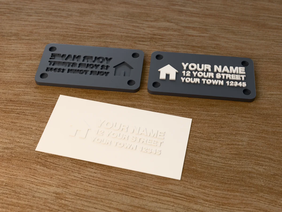 3D render of the printed return address embosser, its two plates side by side, with the raised die and the matching cavity, next to a card embossed with its mark