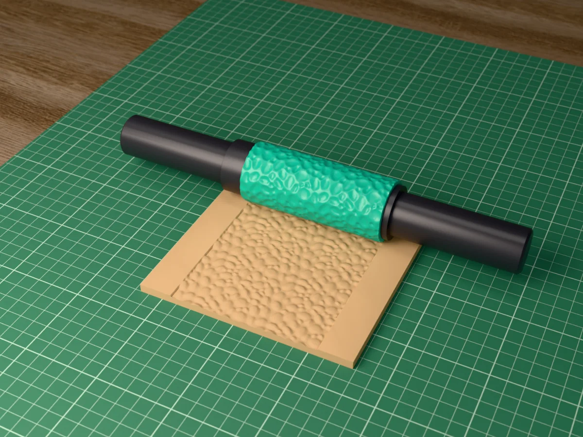 3D render of the printed river pebble textured rolling pin, its patterned sleeve between two dark handles, resting on a slab of clay it has pressed with river pebbles