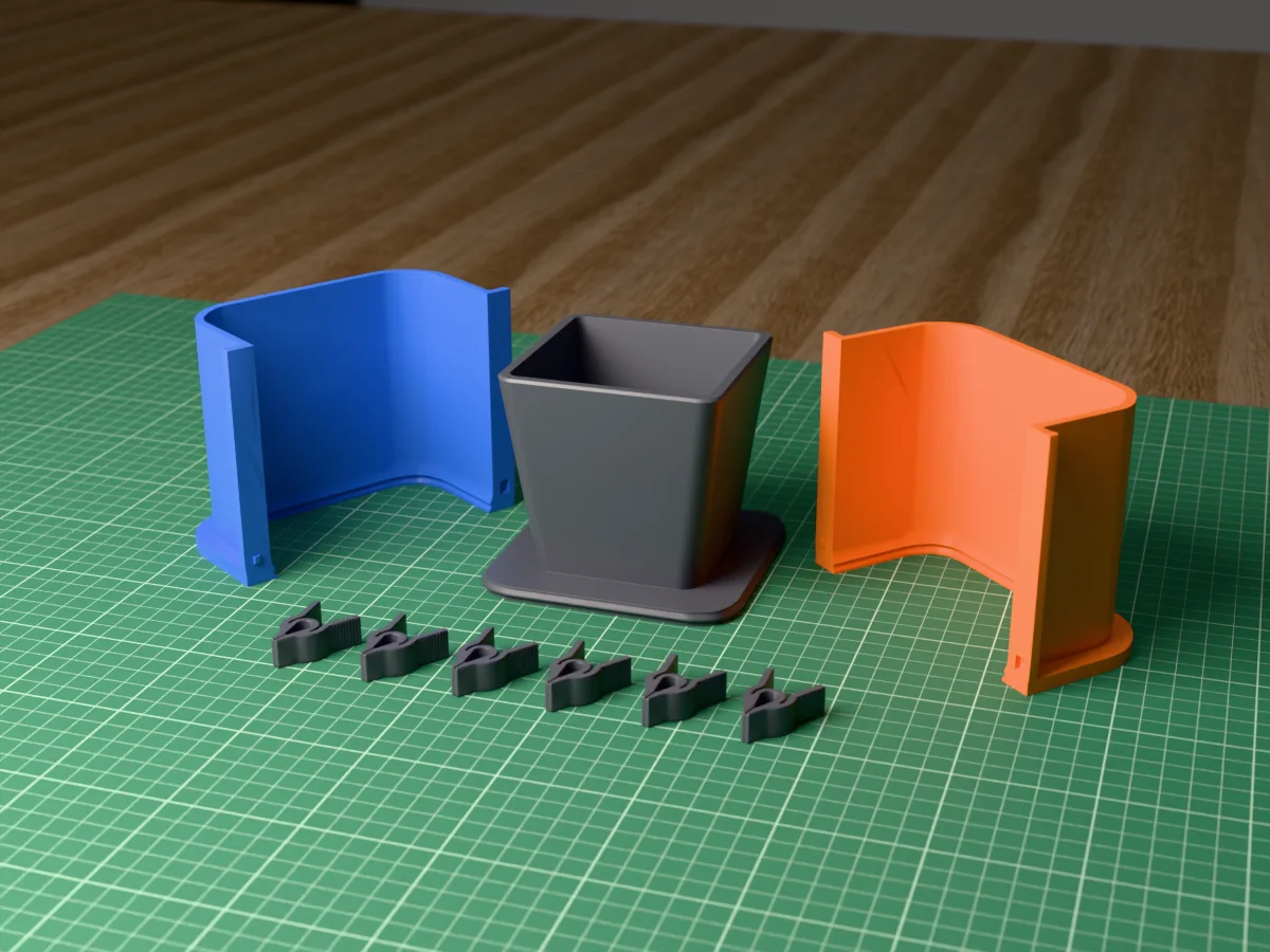 3D render of the tapered square planter master fused on its printed charcoal base, between the orange and blue shell halves, with the charcoal clamps behind