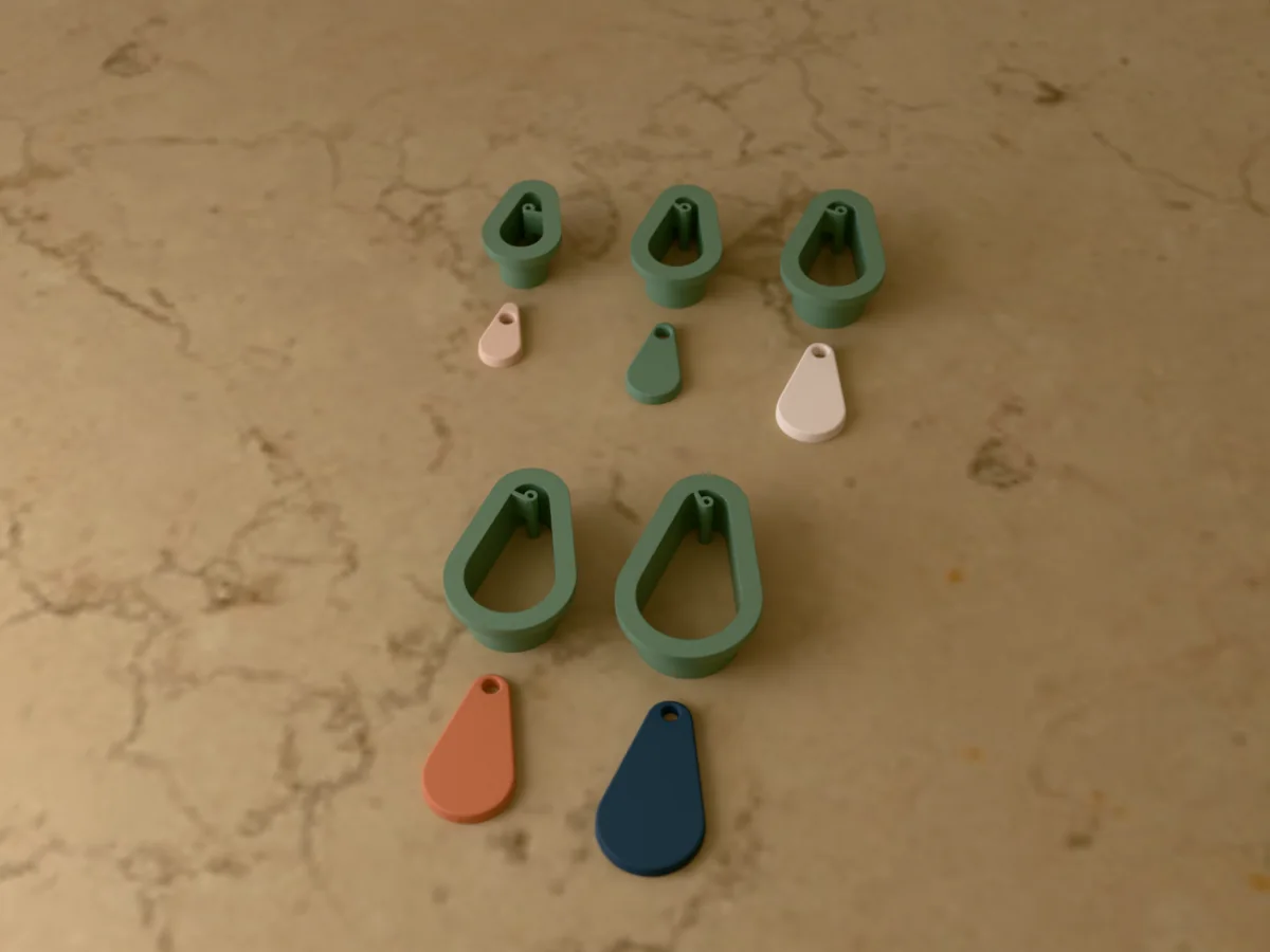 3D render of five 3D-printed sage green polymer clay earring cutters (teardrop 20 mm, teardrop 25 mm, teardrop 30 mm, teardrop 35 mm and teardrop 40 mm) with the clay earring pieces they cut in front