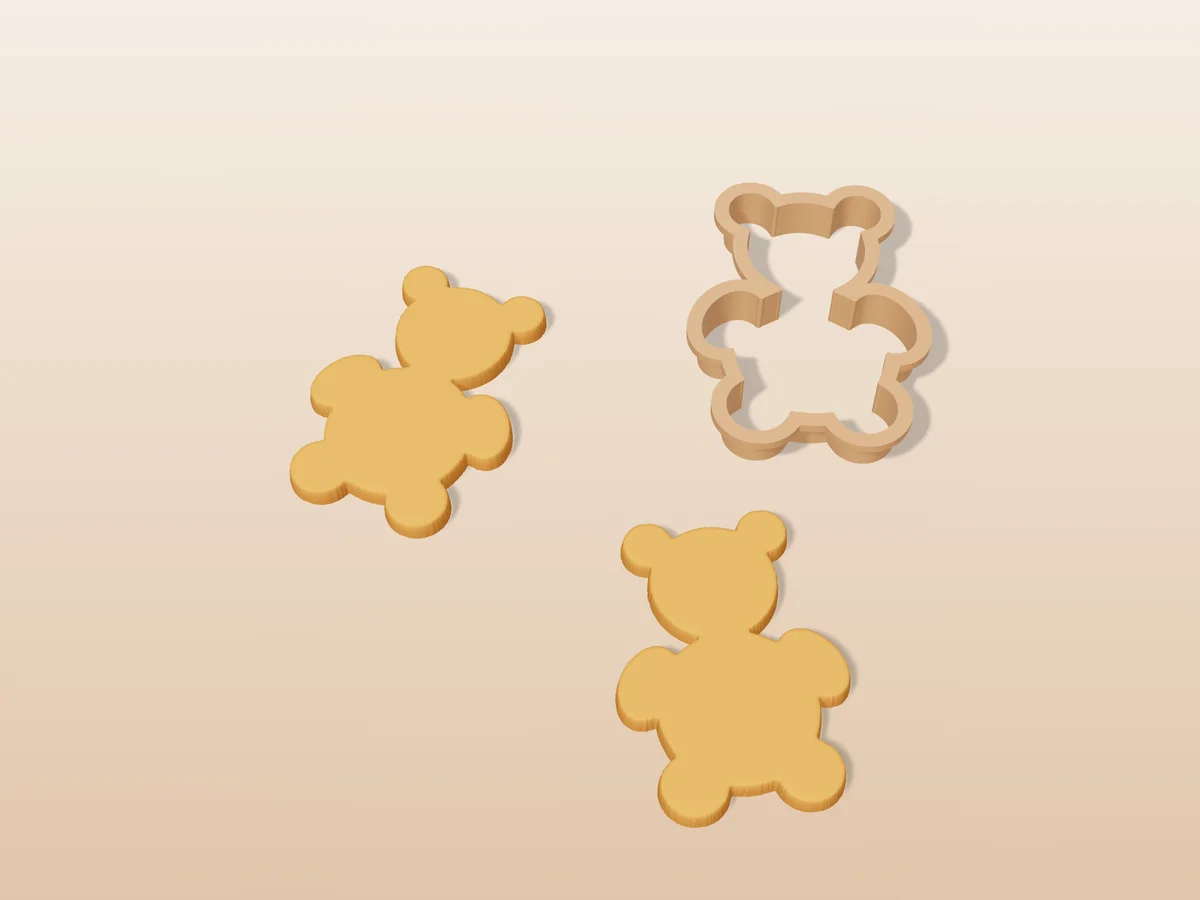 3D render of a tan 3D-printed teddy bear cookie cutter next to two golden baked cookies in the same shape