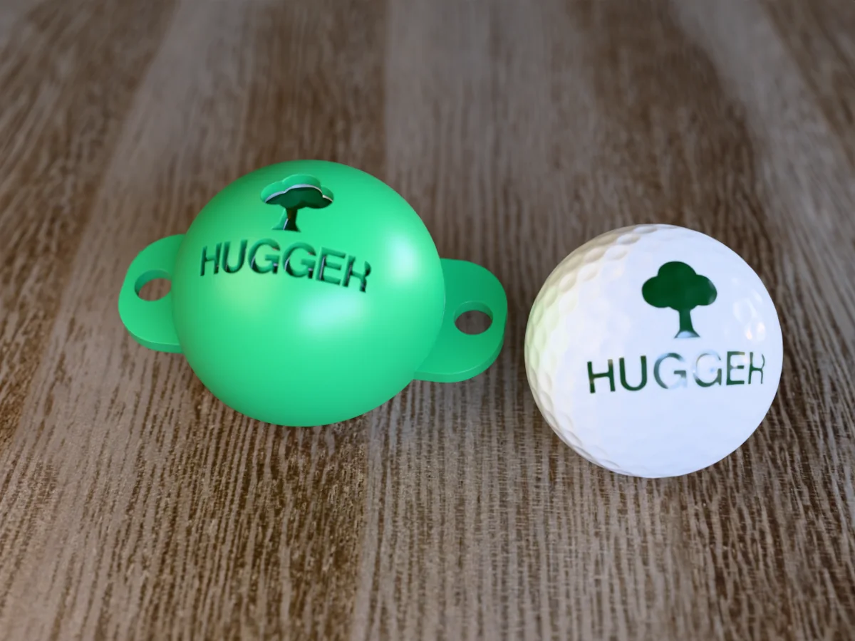 3D render of a green 3D-printed golf ball stencil with a tree over HUGGER cut through it, sitting on a golf ball, next to a ball marked with a tree over HUGGER in green