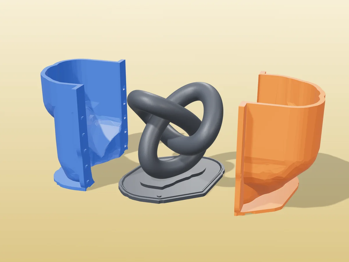 3D render of the trefoil knot master fused on its printed charcoal base, between the orange and blue hugging shell halves