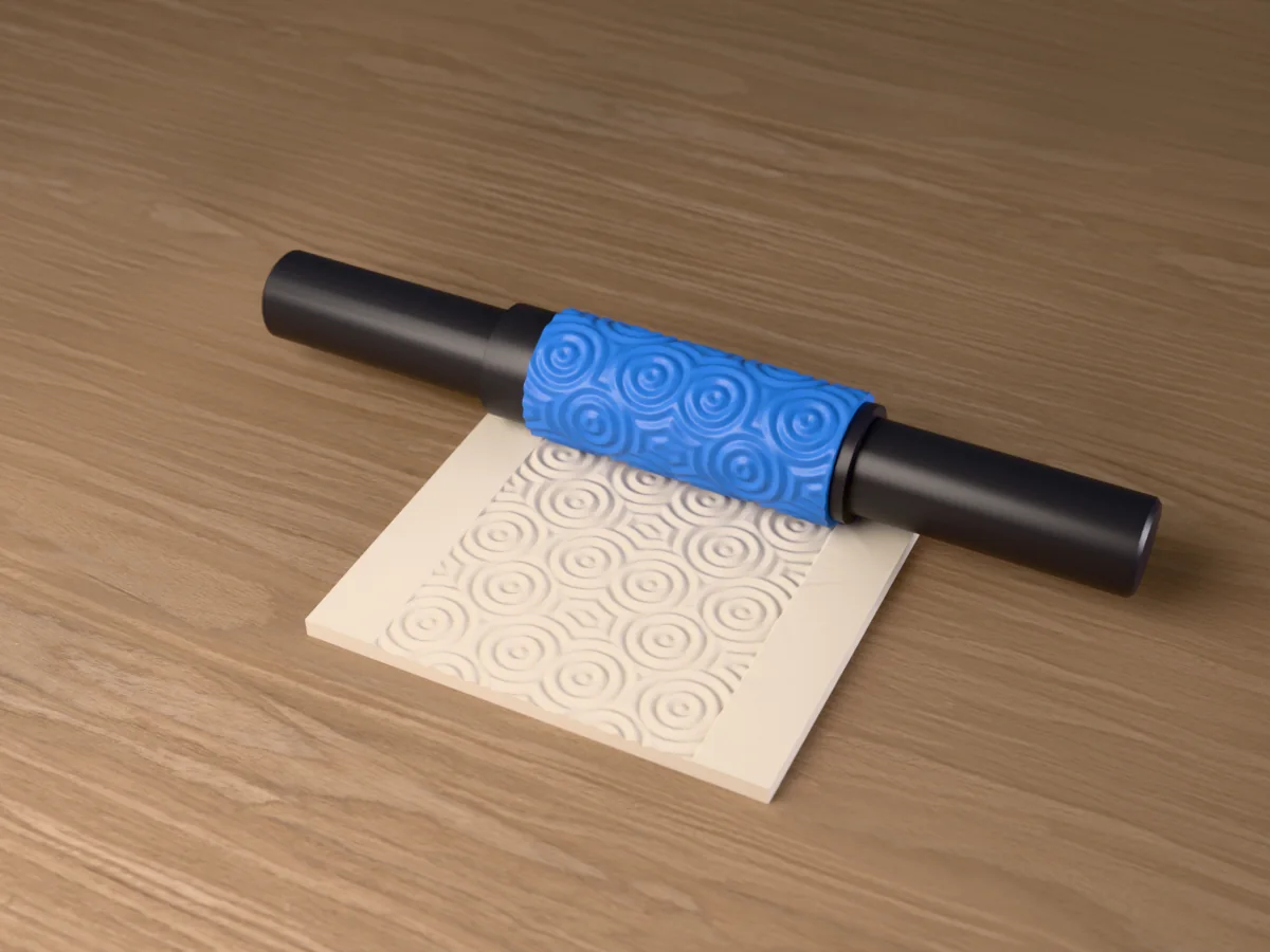 3D render of the printed water ripple textured rolling pin, its patterned sleeve between two dark handles, resting on a slab of clay it has pressed with water ripples