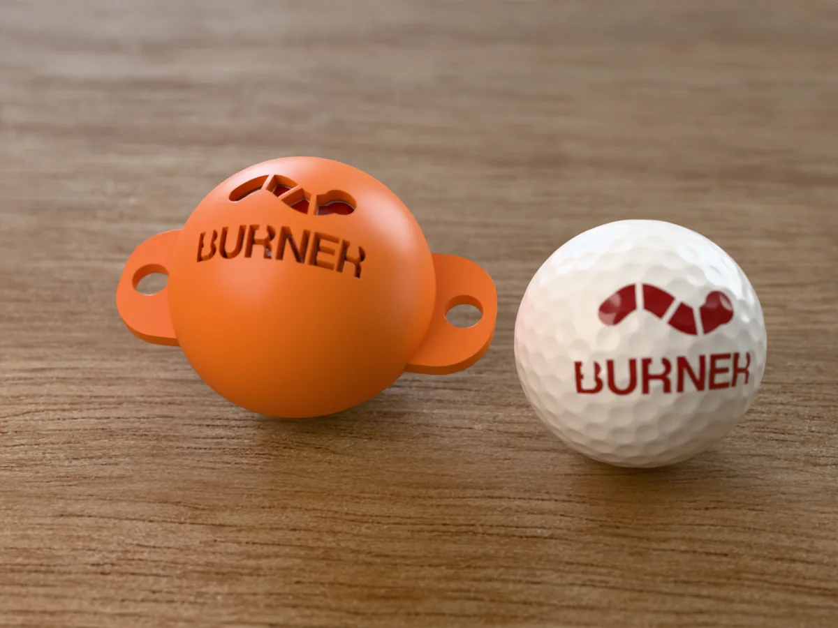 3D render of an orange 3D-printed golf ball stencil with a worm over BURNER cut through it, sitting on a golf ball, next to a ball marked with a worm over BURNER in red