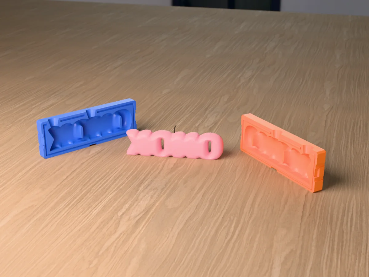 3D render of a XOXO bubble letter candle between the two printed halves of its rigid orange and blue mold