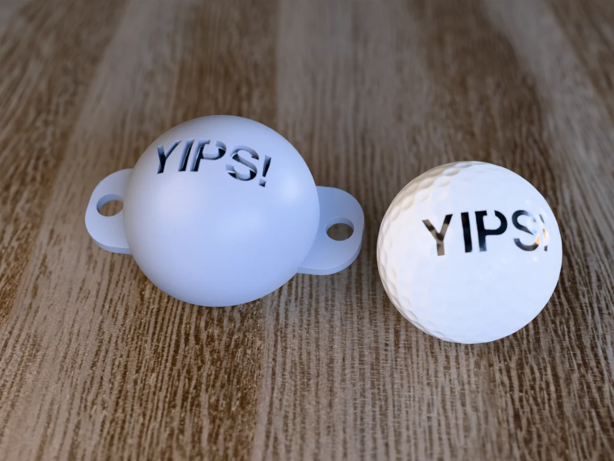 3D render of a grey 3D-printed golf ball stencil with YIPS! cut through it, sitting on a golf ball, next to a ball marked with YIPS! in black