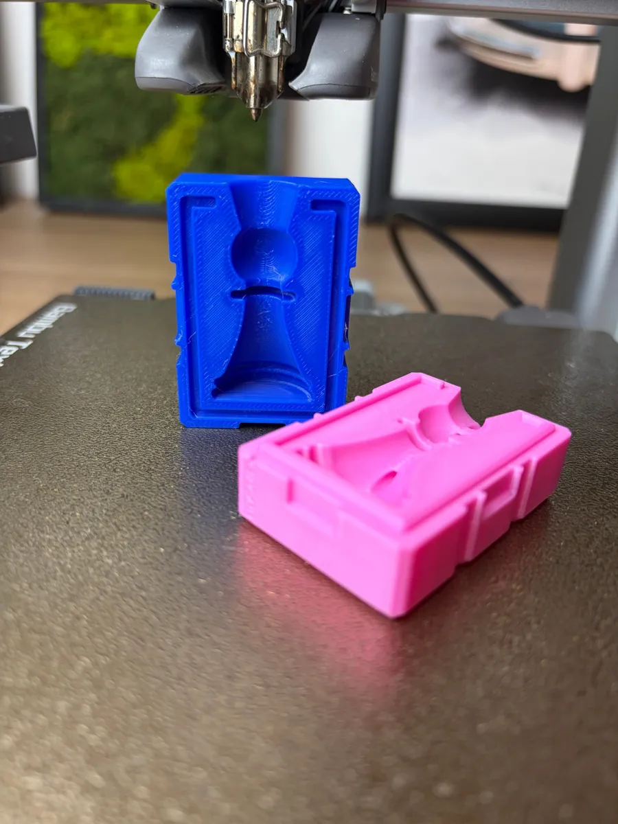 The blue half of the printed chess pawn mold stood upright, the pawn cavity, rubber-band grooves and pry pockets in view, the pink half in front