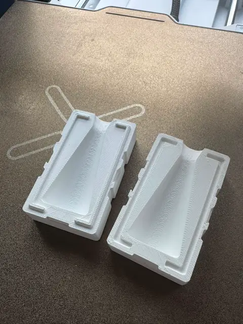A pair of printed two-part candle mold halves on a desk with rubber bands beside them