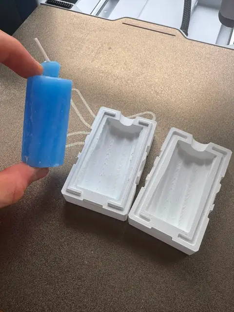A freshly cast wax candle beside its 3D-printed two-part mold.