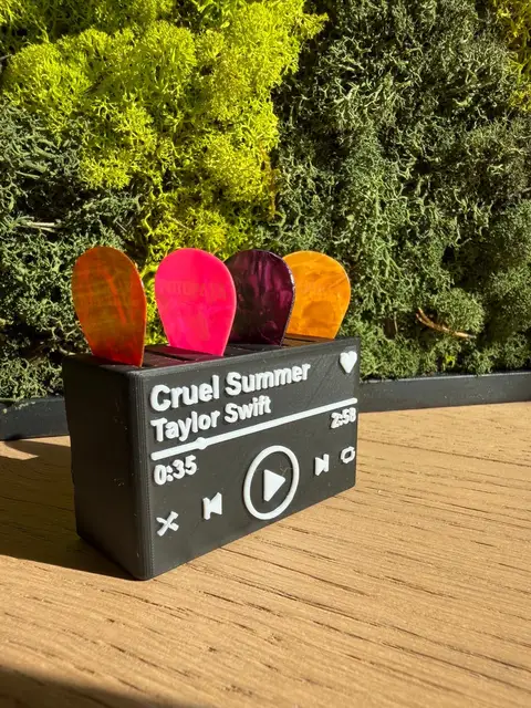 A finished now-playing music card stand with four coloured guitar picks slotted into the top.