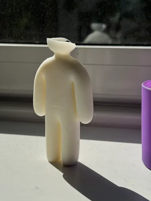 A wax figure candle fresh out of its 3D-printed two-part mold, the cone-shaped pour funnel still attached at the top and not yet trimmed off.