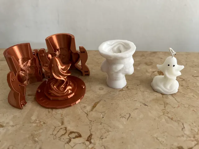 A copper 3D-printed two-part ghost mold open beside its master, with the white cast and the finished wax ghost candle.