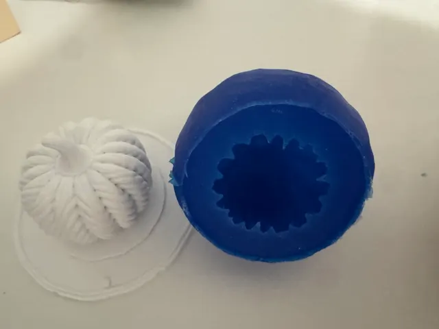 A blue silicone negative mold next to the white plaster gourd it cast, both freshly demolded.