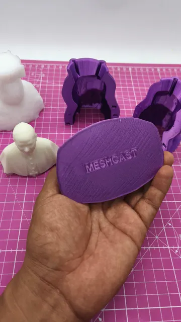 A purple printed mold lid with MESHCAST embossed across it, held in front of the matching two-part bust molds and a white cast. Made by @punto3dperu.