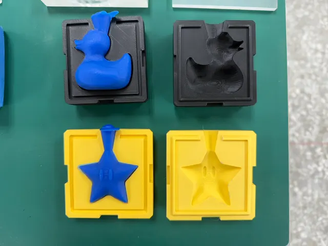 Black and yellow two-part molds laid out in pairs with their blue duck and star masters, ready for paraffin.