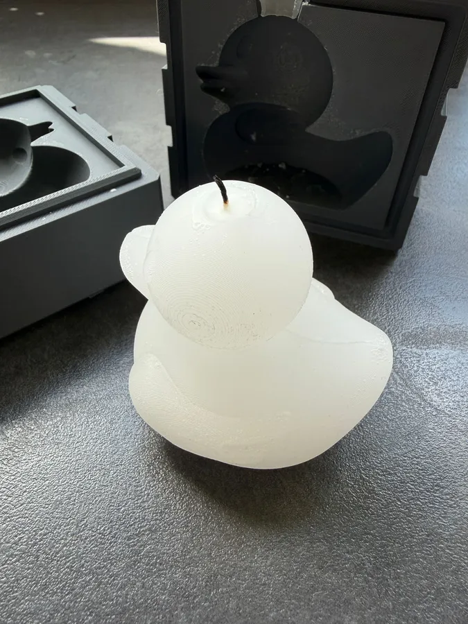 A rubber-duck candle in front of the two-part mold it was cast from.